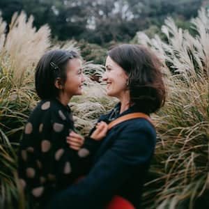 A mother and her daughter cuddling surrounded by pampas grass